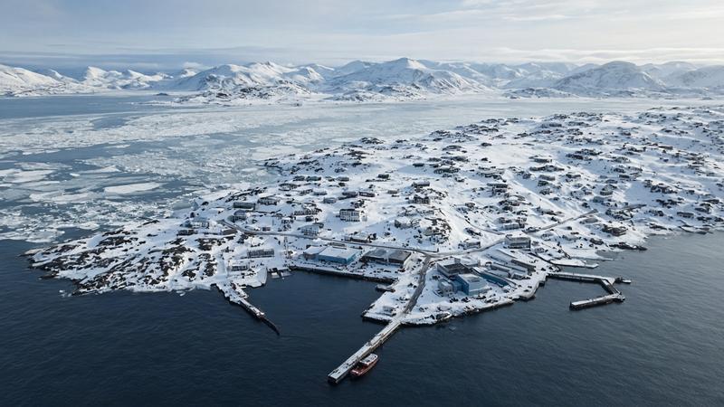 Aerial view of a snowy Arctic coastal town and harbor
