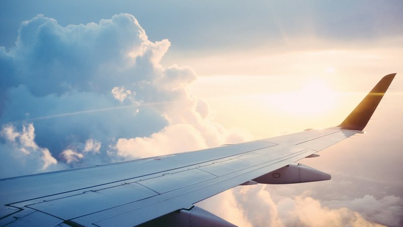 Airplane wing above clouds during long-haul travel