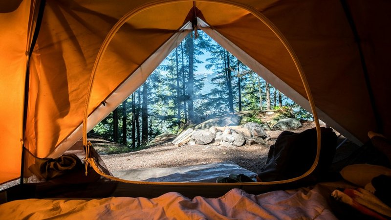 Tent camping outdoors at dusk, illustrating traditional camping versus glamping
