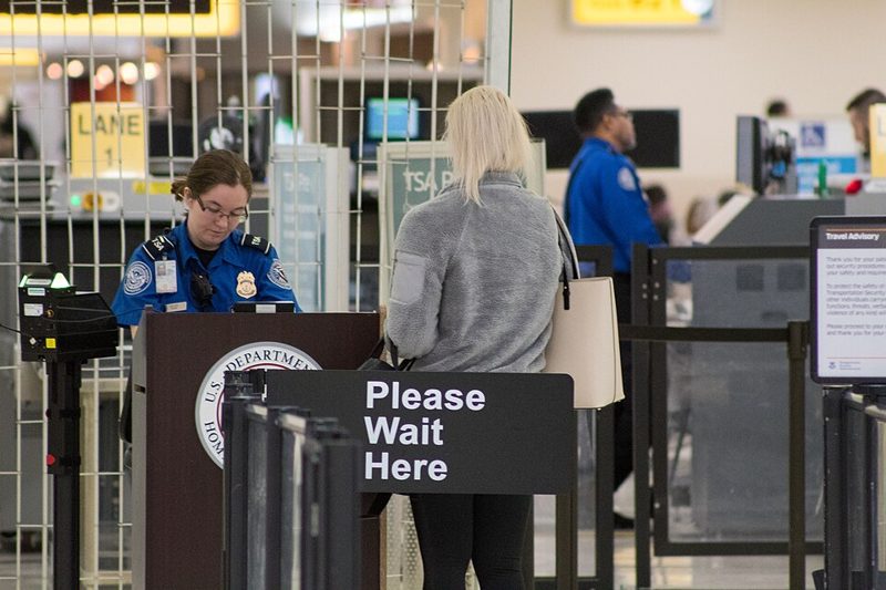 TSA officer checking a traveler at an airport security checkpoint