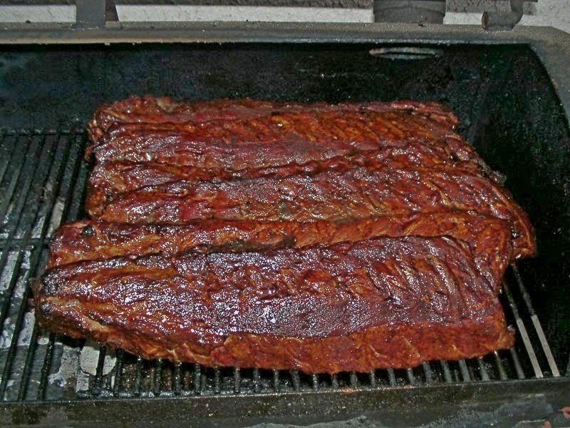 Racks of hickory-smoked baby back pork ribs on a smoker grill