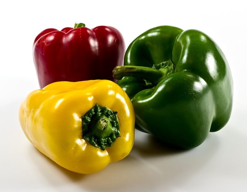 Red, yellow and green bell peppers on a white background