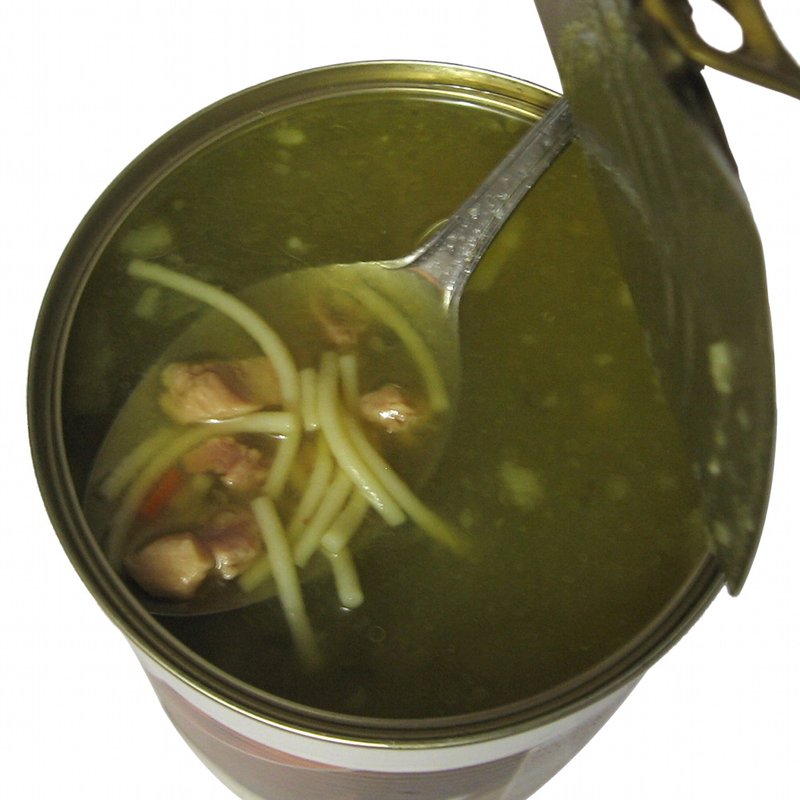 An opened can of chicken soup with a spoon resting in the can