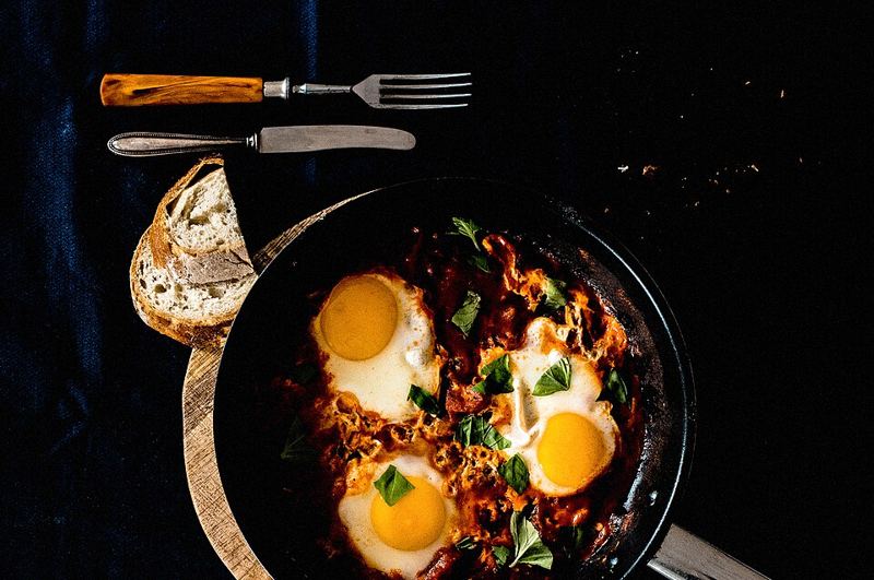 Shakshuka with eggs simmered in tomato sauce in a skillet