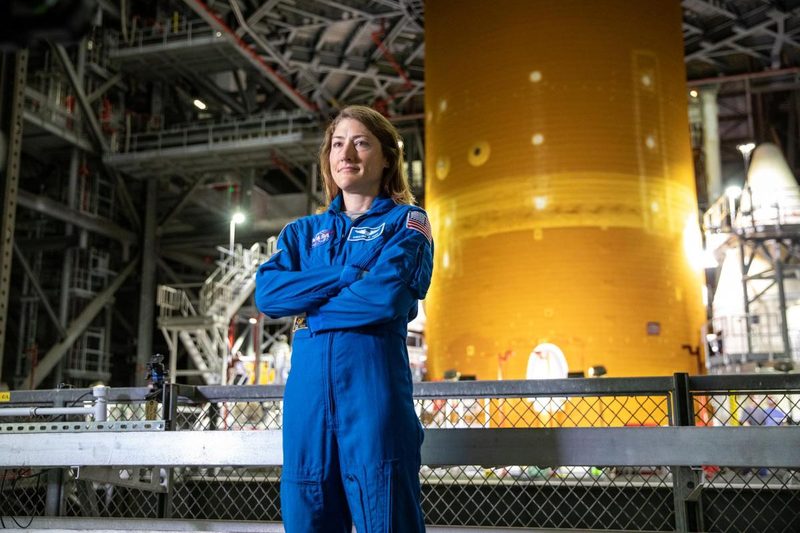 NASA astronaut Christina Koch stands inside Kennedy Space Center Vehicle Assembly Building in front of the Space Launch System rocket