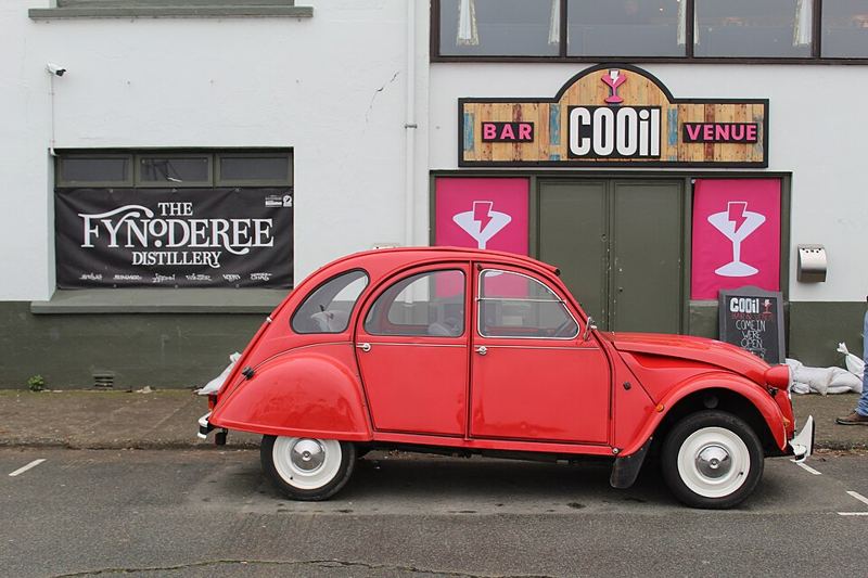 A red original Citroën 2CV parked on a street