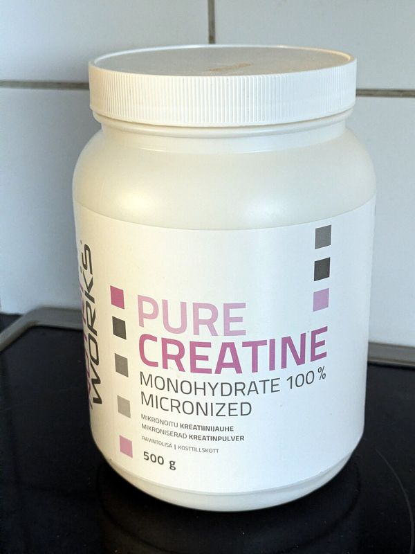 White tub of micronized creatine monohydrate powder on a kitchen counter
