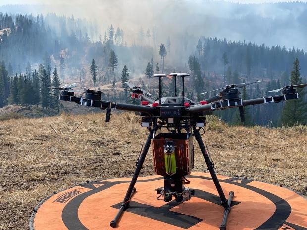 DJI Matrice 600 Pro drone on a landing pad near a forest fire