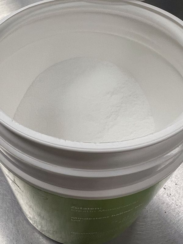 Open tub of white creatine monohydrate powder