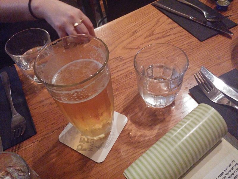 A glass of beer and glasses of water on a wooden restaurant table