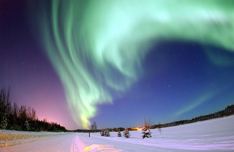 Green northern lights over a snowy landscape