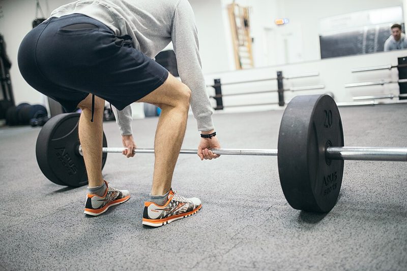 A man performing a barbell deadlift in a gym