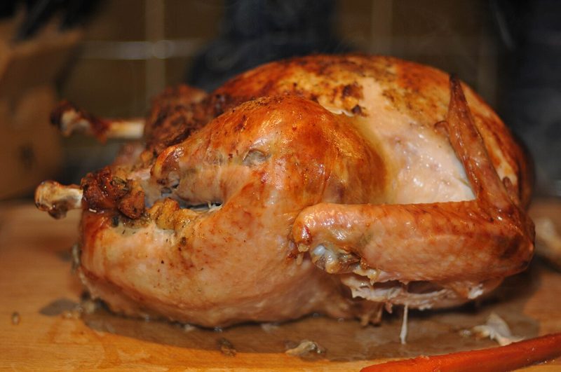 Whole roast turkey on a carving board, cooked using a how long to cook a turkey time chart