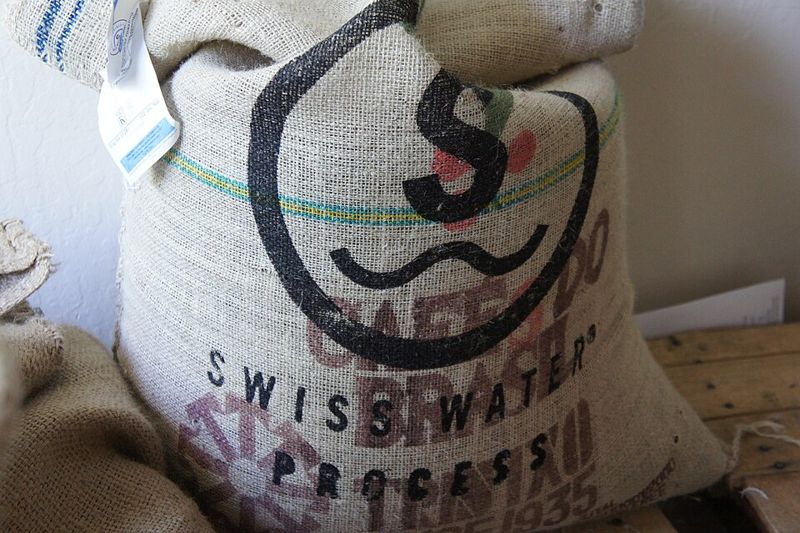 Burlap sack of green decaffeinated Brazilian coffee beans stamped Swiss Water Process