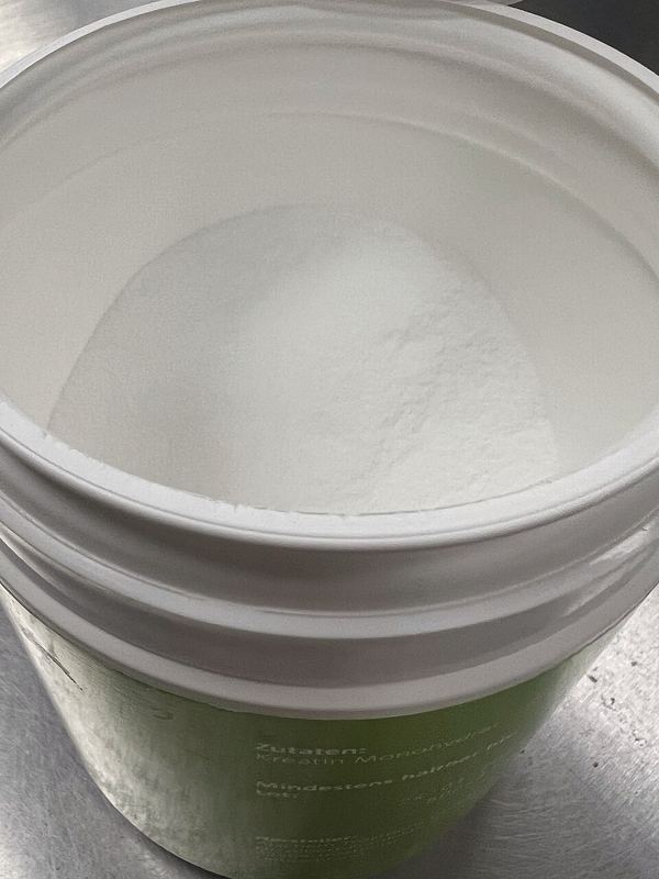 Open tub of white creatine monohydrate powder