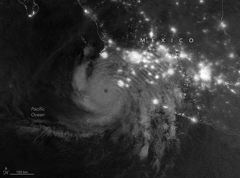 Black-and-white nighttime satellite view of Hurricane Simon beside the lit coast of Mexico