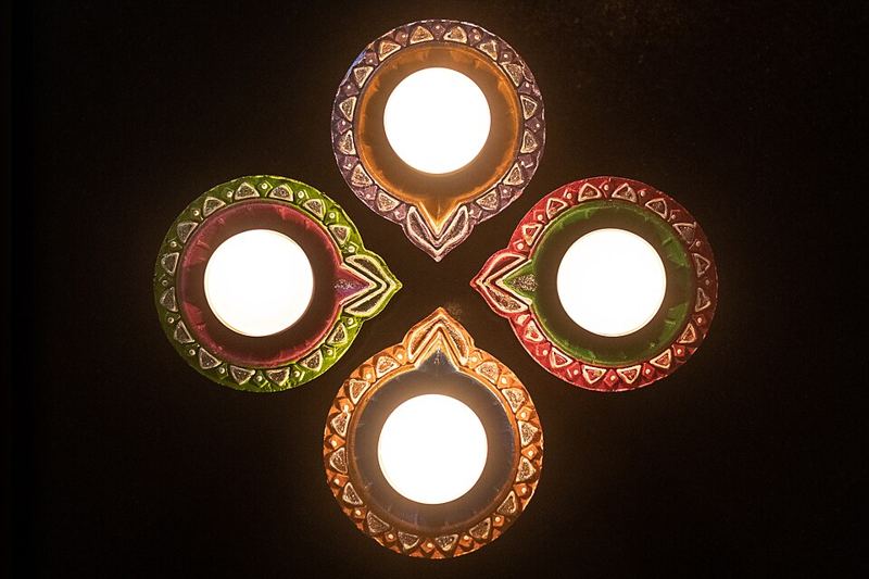 Four lit clay diya lamps arranged in a circle for Diwali
