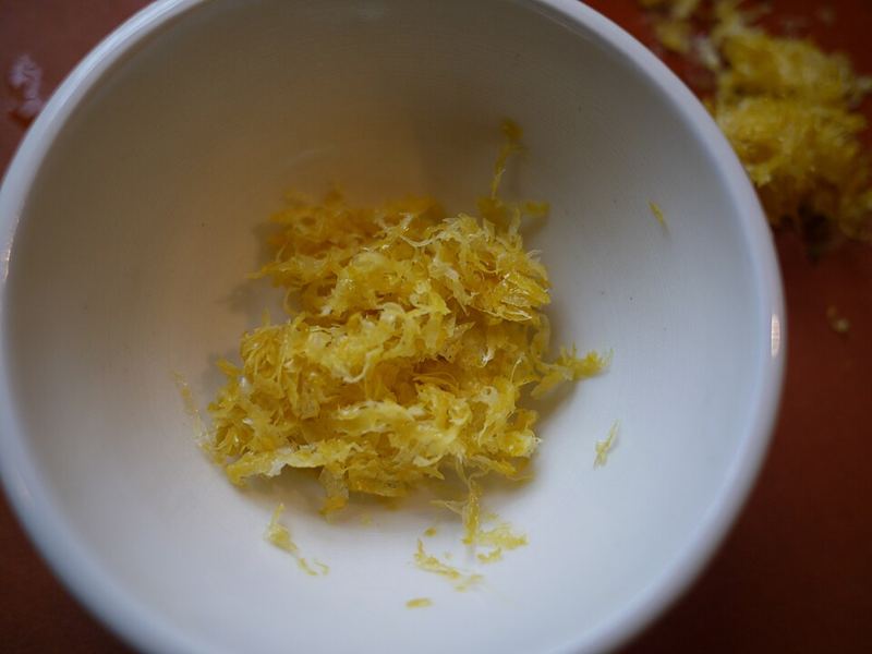 Freshly grated lemon zest next to a lemon