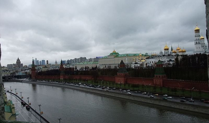 The Moscow Kremlin walls, palaces and gold-domed cathedrals beside the Moskva River under a cloudy sky