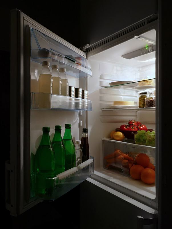 Open refrigerator lit up in a dark kitchen at night