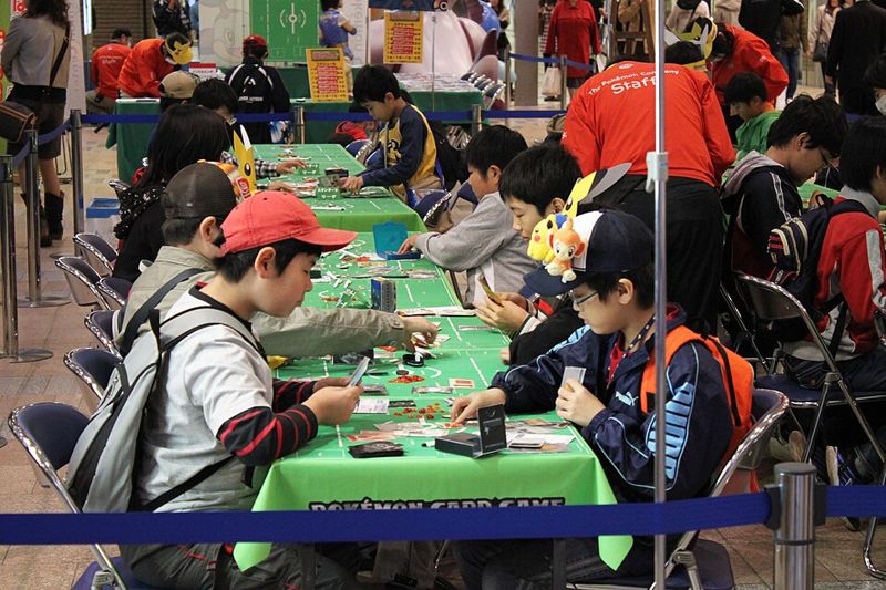 Children playing the Pokémon Trading Card Game at a tournament table