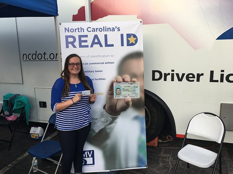 Woman holding her new North Carolina REAL ID card with the star, showing REAL ID requirements in practice