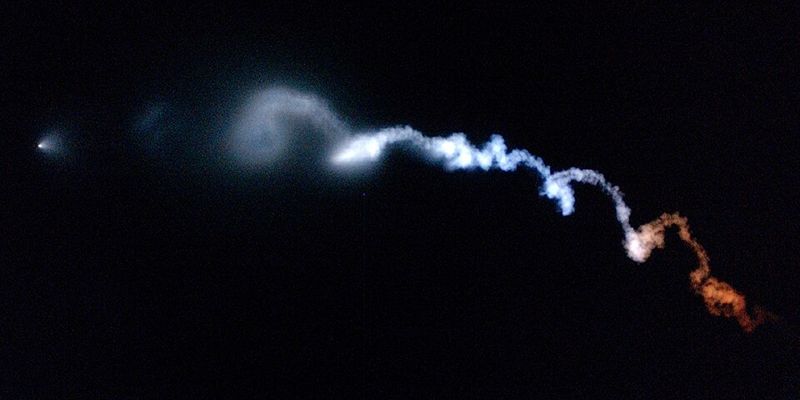 Glowing twilight exhaust plume spreading across the sky after a rocket launch