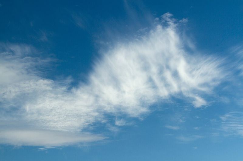 Thin white high-altitude cirrocumulus and cirrus clouds against a blue sky over Bergsfjorden, Norway