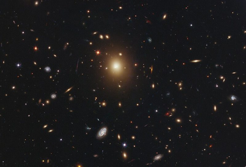 Hubble Space Telescope image of galaxy cluster Abell 2261, with a large bright elliptical galaxy at the center surrounded by many smaller galaxies