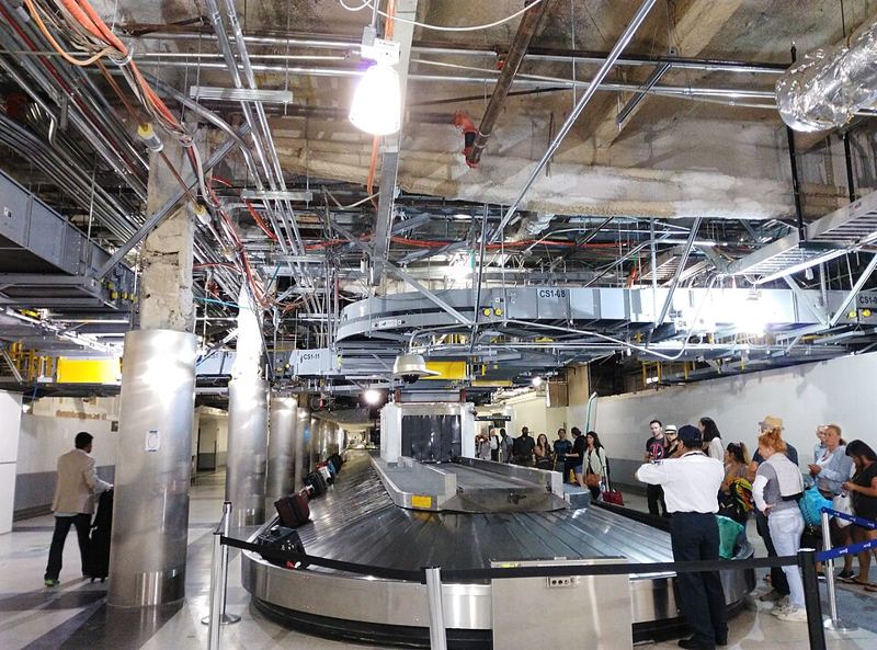 Travelers waiting at a baggage claim carousel at Los Angeles International Airport