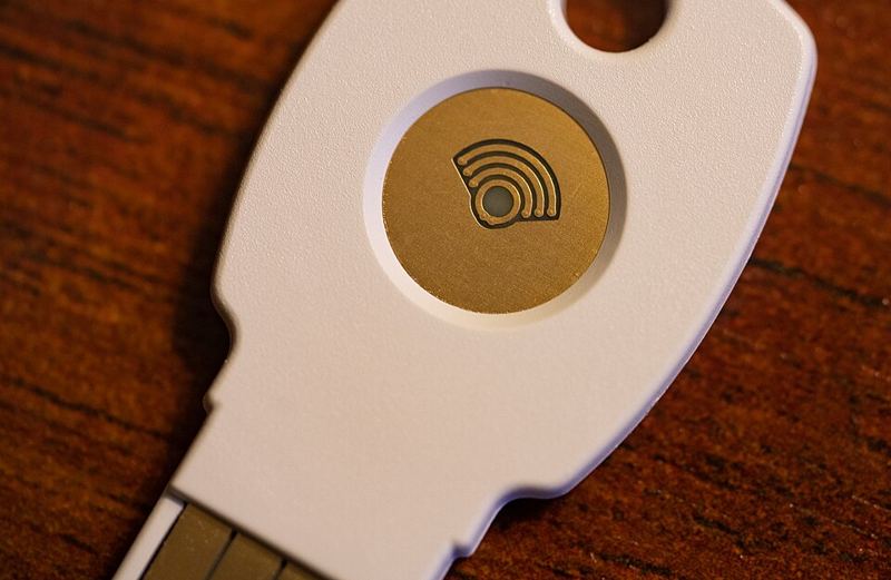 Close-up of a white Google Titan USB security key with a gold touch sensor, a hardware key that can store a device-bound passkey