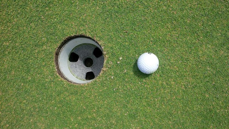 Golf ball resting on a putting green next to the hole