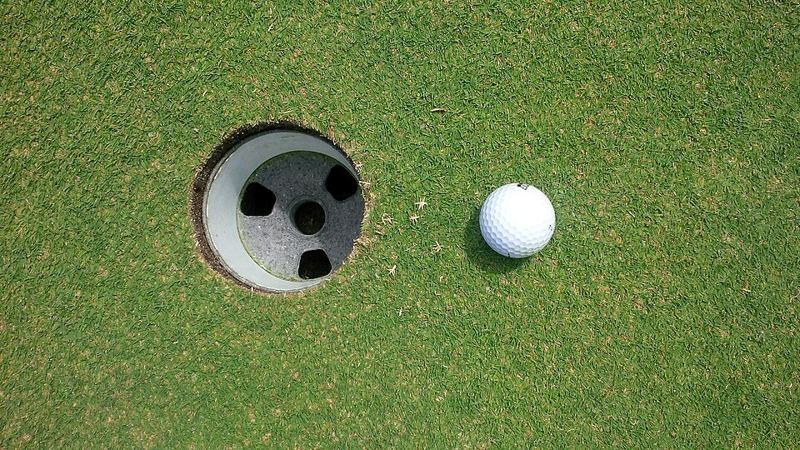 Golf ball resting on a putting green beside the hole
