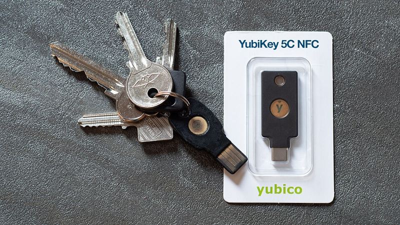 A YubiKey 5C NFC hardware security key in its packaging next to a set of house keys