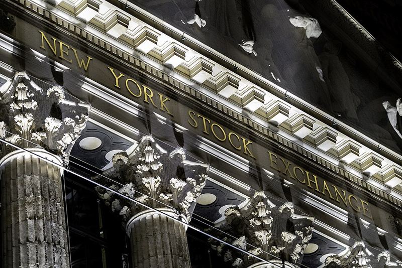 Gold lettering reading New York Stock Exchange on the building's columned facade at night