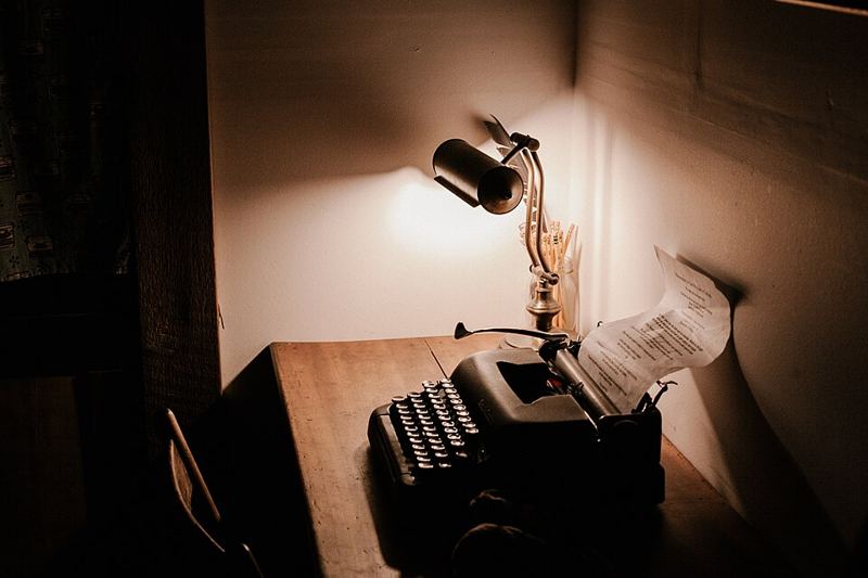A vintage typewriter with a typed page on a wooden desk under a lamp