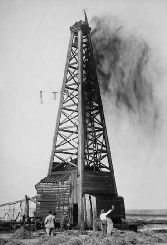 A wooden oil derrick with a crude oil gusher spraying into the air at Okemah, Oklahoma, in 1922