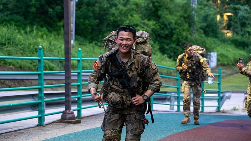 U.S. Army soldiers walking on a path while carrying heavy rucksacks during a 12-mile ruck march