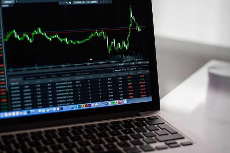 A laptop screen showing a financial price chart and a table of trading data