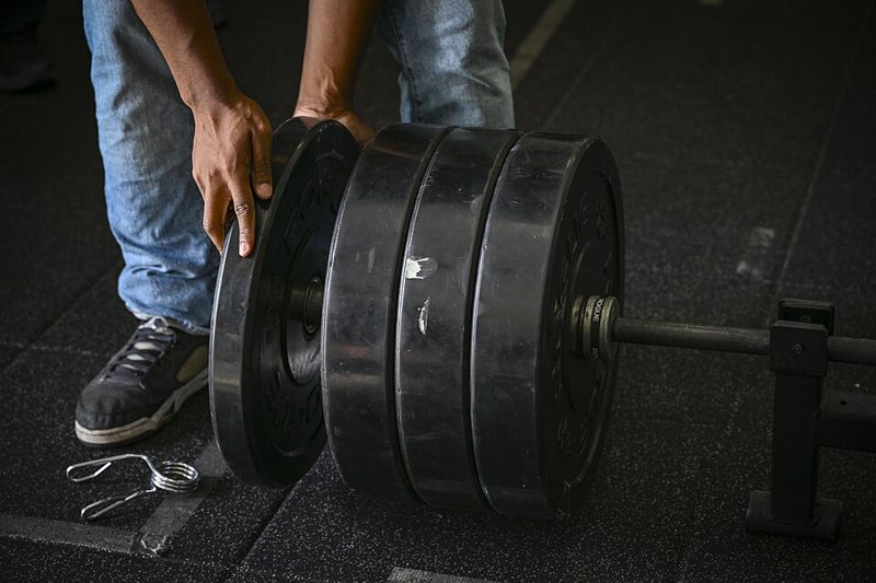 Weight plates being loaded onto a barbell at a powerlifting competition
