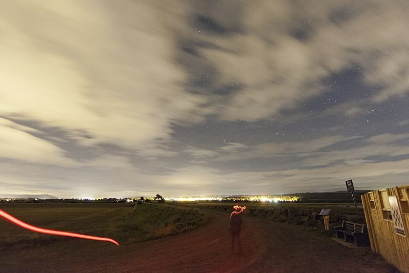 Partly cloudy night sky with stars over a field during a Draconid meteor shower watch