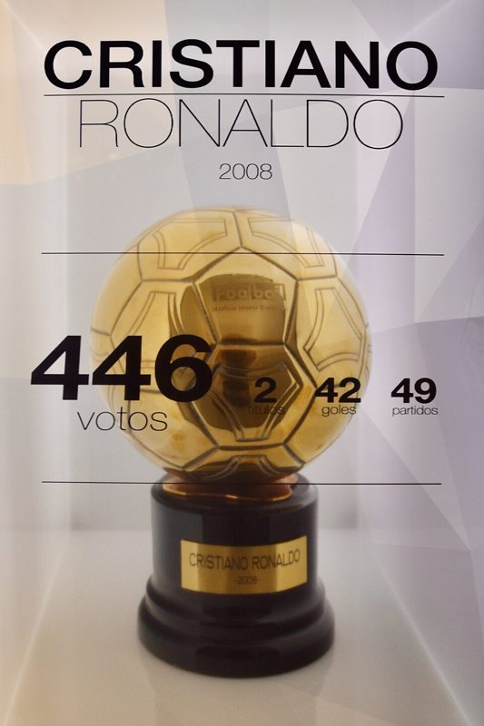 A golden Ballon d'Or trophy on display in a museum case