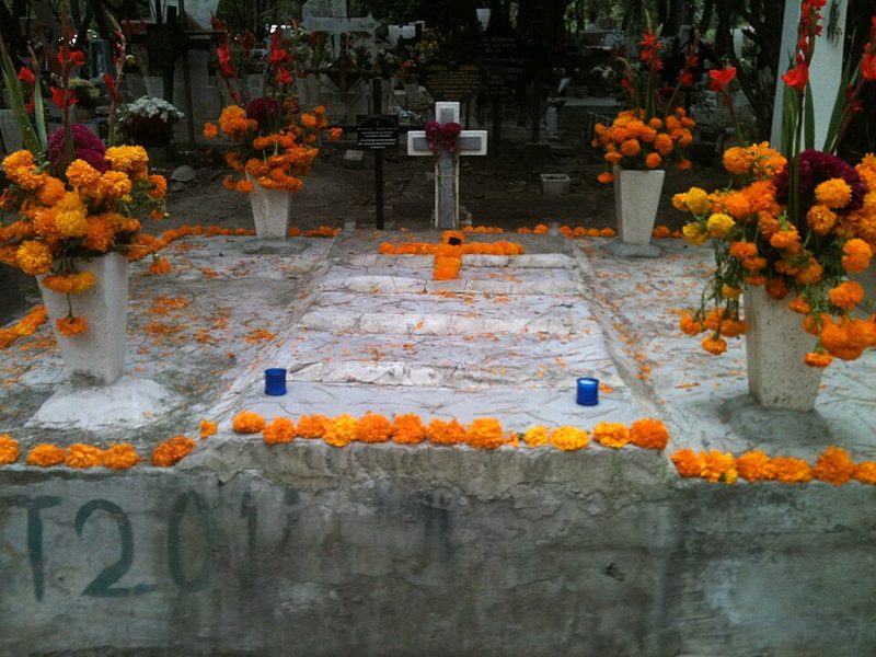 Grave decorated with orange cempasuchil marigolds, marigold petals and candles for Day of the Dead in a Mexican cemetery