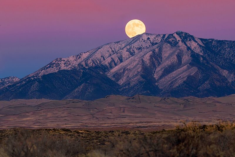 November full Beaver Moon rising over the sand dunes and Mount Zwischen at Great Sand Dunes National Park, Colorado