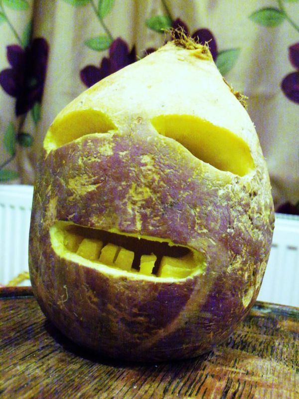 A turnip carved with eyes and a toothy grin as a traditional jack-o'-lantern